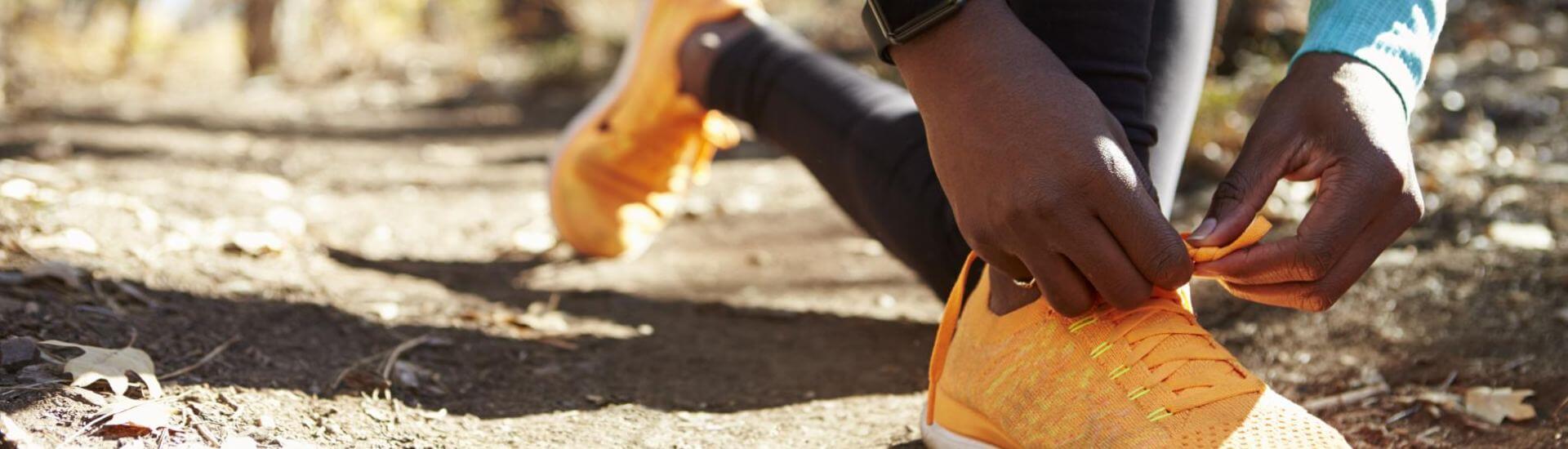 woman tying shoes on forest trail